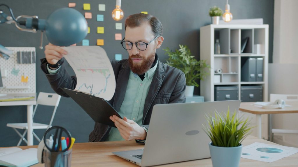 Un homme dans un bureau examine des documents sur son bureau.